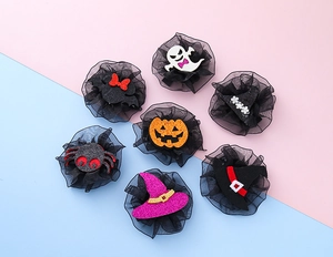 Detail view of 7 glittery Halloween hair clips including pumpkin, ghost, and bat shapes