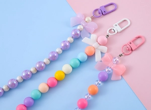 Three colorful beaded keychains with bow charms in purple, macaron, and coral pink