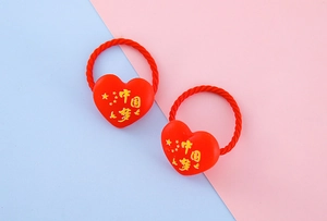 Détail de deux chouchous en résine en forme de cœur rouge avec motifs chinois et étoiles