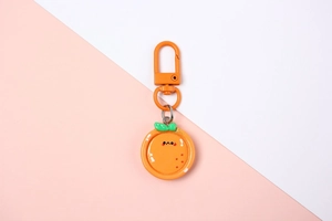 Close-up of cute resin orange fruit keychain with a minimalist face and metal clasp