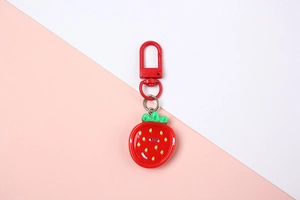Close-up of a cute resin strawberry keychain with a red hook and a minimalist happy face