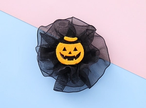 Detail of Halloween hair clip featuring an orange pumpkin face and black mesh tulle petals