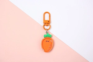 Close-up of cute cartoon carrot resin keychain with green leaves and orange metal clasp