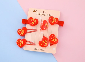 Détail des pinces à cheveux coeur en résine rouge et élastiques avec motifs d'étoiles