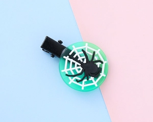 Close-up of Halloween hair clip with white spider web and black spider on green base