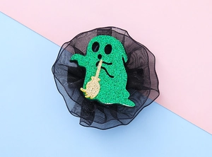 Detail of sequin green ghost hair clip with gold broom and black mesh trim décor