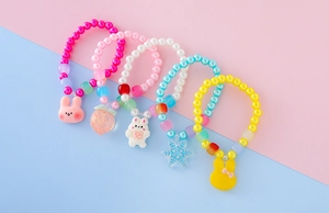 Dettaglio di braccialetti con perline colorate e ciondoli di animali per bambine