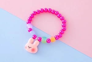 Dettaglio di un braccialetto colorato per bambini con ciondolo a coniglio rosa e perle