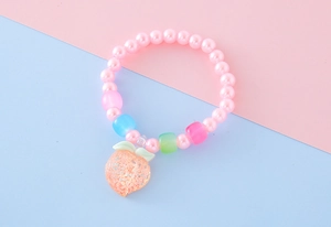 Dettaglio del braccialetto di perle rosa per bambini con un ciondolo a forma di pesca