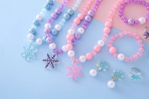 Detailed flat lay of children snowflake jewelry set with beaded necklaces and rings