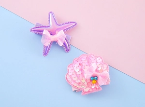 Detailed close-up of girls starfish and seashell hair clips with sequins and bows