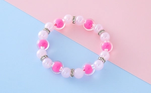 Détail des perles nacrées roses et des perles à cœur magenta sur bracelet élastique
