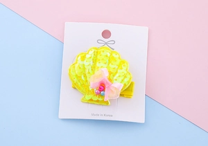 Detail of yellow sequin shell hair clip with pink mesh bow on a display card