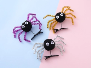 Detailed view of Halloween spider hair clips in purple, gold, and silver with plush balls