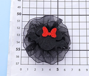 Detail view of black bat hair clip with red glitter bow and mesh on scale mat