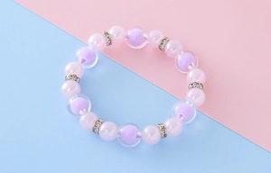 Gros plan d'un bracelet élastique en perles macaron pastel avec strass et perles mauves