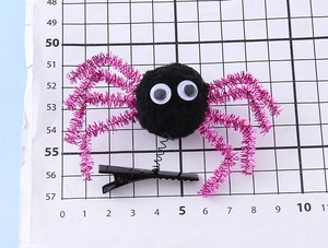 Detailed macro view of a Halloween spider hair clip with purple glitter legs on scale paper
