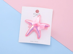 Detailed view of pink iridescent starfish hair clip with soft mesh bow and bead edges