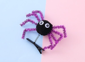 Close-up of Halloween spider hair clip with purple glitter legs on a spring metal base