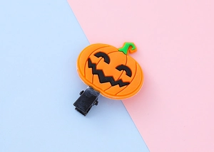 Gros plan d'une pince à cheveux citrouille d'Halloween en PVC souple avec clip métallique noir