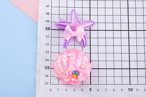 Detailed view of starfish and sequin shell hair clips with size measurements