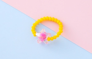 Dettaglio dell'anello con perline gialle e ciondolo a stella trasparente per bambini piccoli