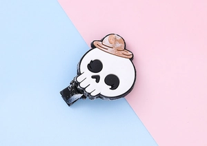 Détail d'une pince à cheveux tête de mort d'Halloween avec chapeau marron et décor bicolore