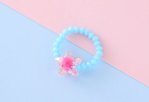 Dettaglio dell'anello elastico per bambini con perle blu e ciondolo a stella