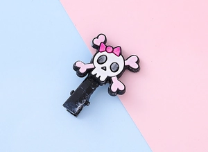 Détail d'une pince à cheveux crâne avec nœud rose et os en cœur sur fond pastel