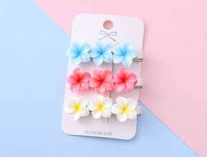 Drei plumeria-haarspangen aus kunstharz in blau, rosa und weiß auf einer karte