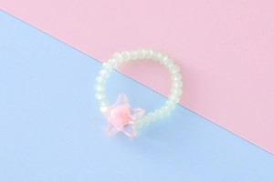 Dettaglio macro dell'anello di perline con ciondolo a stella traslucido e fiore rosa