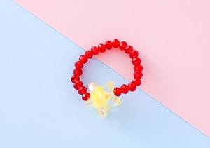 Dettaglio dell'anello elastico con perline rosse sfaccettate e ciondolo a stella