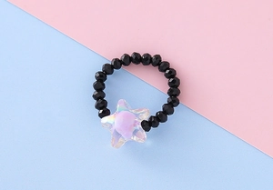 Dettaglio ravvicinato di un anello di perle nere con una stella centrale sfumata viola