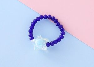 Primo piano dell'anello elastico con perline per bambini e ciondolo a stella blu