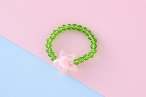 Dettaglio anello di perline verdi per bambini con stella rosa su sfondo colorato