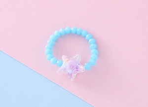 Dettaglio macro di anello di perline per bambini con perle blu e ciondolo a stella iridescente
