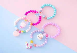 Cinq bracelets de perles colorés avec breloques de dessins animés sur fond pastel