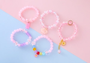 Detail view of five assorted pink and purple beaded bracelets with cute charms for girls
