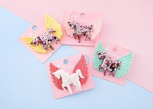Détail de quatre barrettes licorne à paillettes colorées avec des ailes scintillantes pour filles