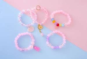 Set of 5 pink beaded bracelets featuring cute gummy bear, daisy and shell charms