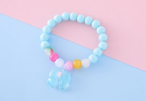 Gros plan du bracelet perlé bleu pour enfants avec un pendentif nœud translucide délicat