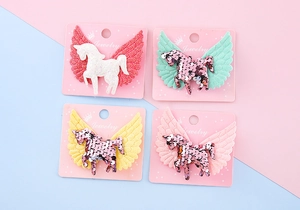 Détail de quatre barrettes ailes de licorne pailletées pour filles sur cartes roses