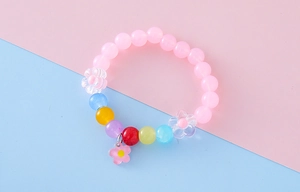 Detail shot of colorful beaded girl's bracelet with pink flower pendant and floral beads