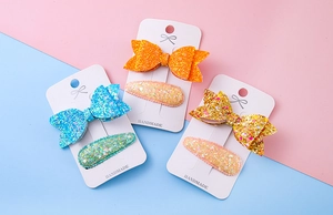 Détail de pinces à cheveux nśud scintillant sur carte en bleu et orange brillant