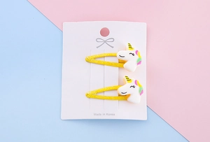 Vista dettagliata di due fermagli per capelli a unicorno con base in metallo giallo glitter