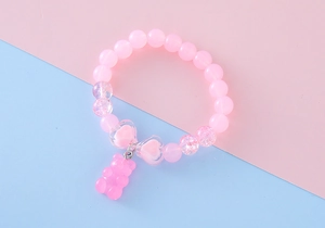 Detailed view of pink beaded bracelet featuring a cute bear pendant and heart charms