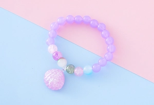 Détail d'un bracelet en perles de résine violettes avec un pendentif coquillage rose