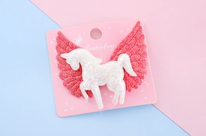 Détail de la pince à cheveux licorne avec ailes pailletées roses sur support carte