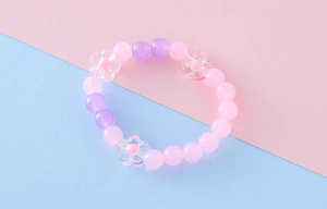 Detail of pink and purple matte beads with transparent flower charms on a kid's bracelet