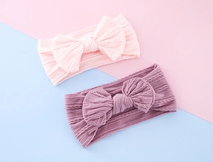 Close-up of baby cable knit headbands with large bows in soft pink and purple tones
